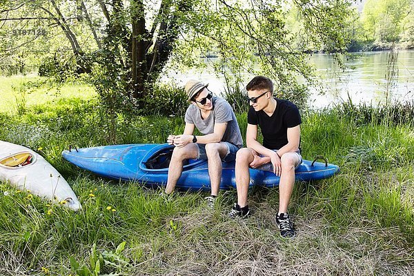 Zwei junge Männer sitzen auf einem Kanu.