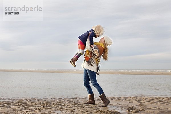 Mittlere erwachsene Frau  die ihre Tochter am Strand aufhebt  Bloemendaal aan Zee  Niederlande