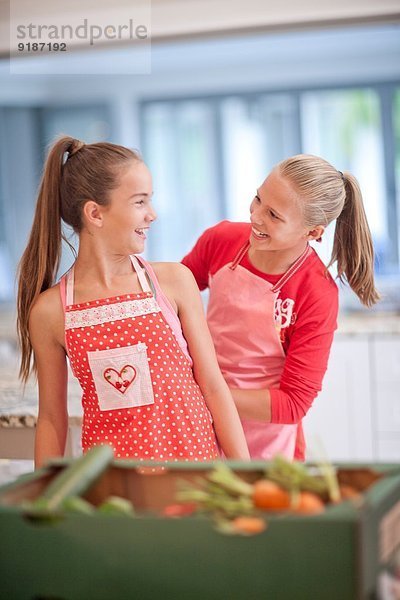Zwei Teenagermädchen bereiten Gemüse in der Küche zu.