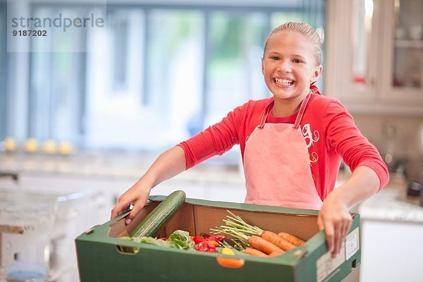 Teenagermädchen mit Gemüsekiste in der Küche