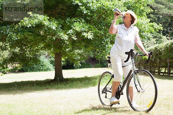 Seniorin Radfahrerin Trinkwasser im Park