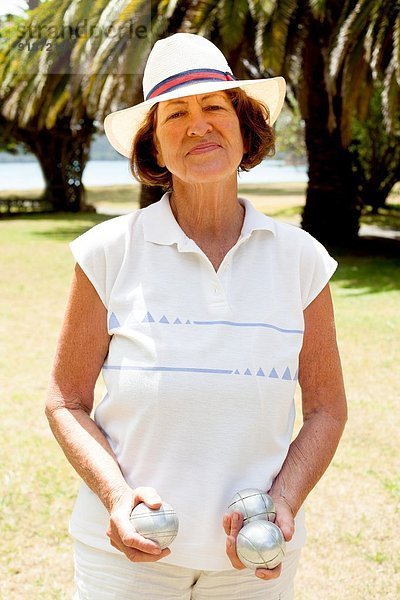 Porträt der Seniorin mit Boulebällen im Park