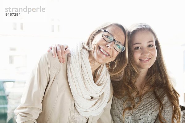 Porträt von Teenagermädchen und Großmutter im Café-Fenstersitz