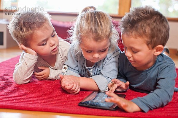 Zwei Jungen und ein Mädchen mit digitalem Tablett im Kindergarten