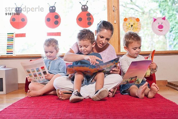 Lehrer und Schüler beim Lesen von Geschichtenbüchern im Kindergarten
