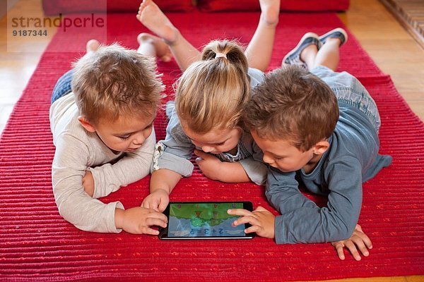 Jungen und ein Mädchen mit digitalem Tablett im Kindergarten