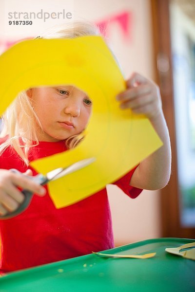 Mädchen beim Ausschneiden von Pappfiguren im Kindergarten