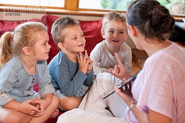 Lehrer mit digitalem Tablett mit Schülern im Kindergarten