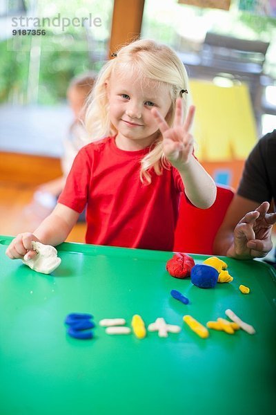 Porträt eines Mädchens beim Zählen mit den Fingern im Kindergarten