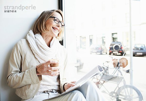 Seniorin bei einem Kaffee im Café-Fenstersitz