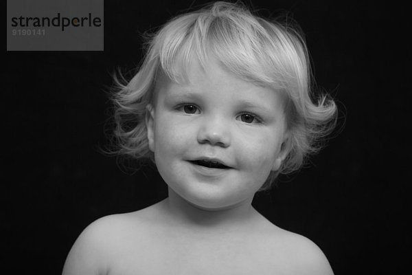 Porträt des süßen Jungen lächelnd auf schwarzem Hintergrund