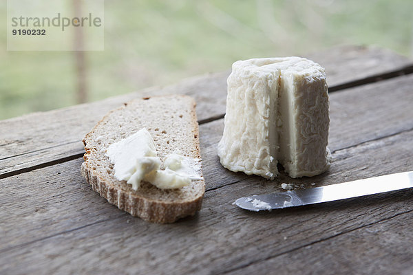 Käse mit Brotscheibe auf Holztisch