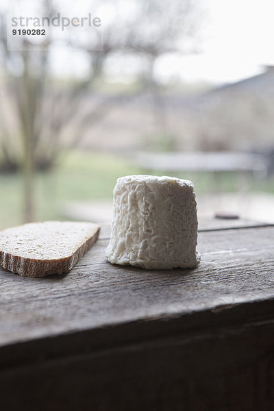 Käse mit Brotscheibe auf Holztisch