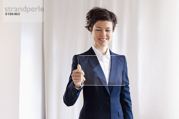 Glückliche  attraktive Geschäftsfrau  die auf ein leeres  transparentes digitales Tablett schaut.