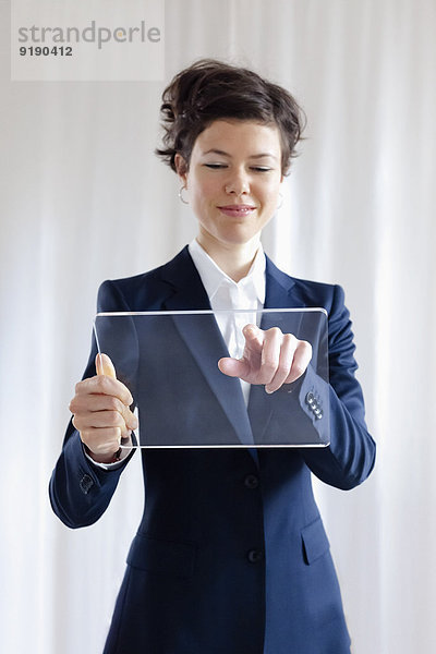 Attraktive mittlere erwachsene Geschäftsfrau beim Berühren eines leeren transparenten digitalen Tabletts