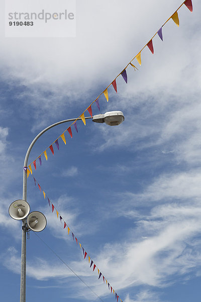Flaggen- und Straßenbeleuchtung mit Lautsprechern gegen bewölkten Himmel