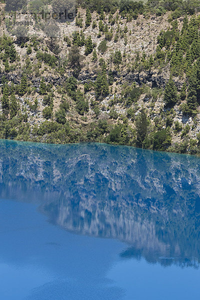 Spiegelung von Bäumen und Felsen im blauen Wasser