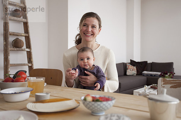 Lächelnde Mutter sitzend mit dem Mädchen am Tisch