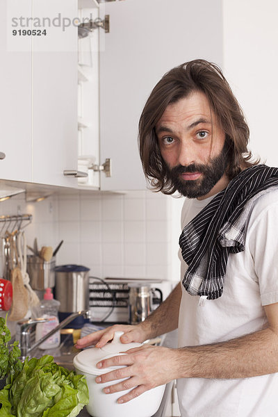 Porträt des Mannes beim Kochen in der heimischen Küche