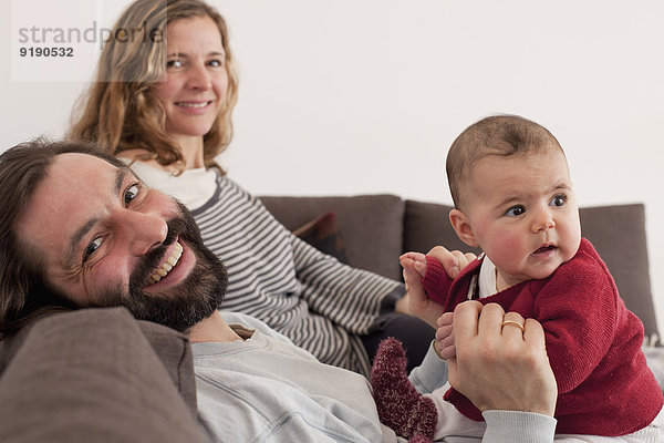 Porträt glücklicher Eltern mit Mädchen auf dem Sofa
