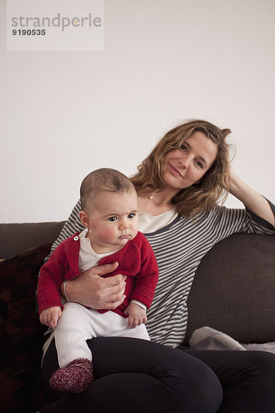 Porträt einer Frau  die mit einem kleinen Mädchen auf dem Sofa sitzt.