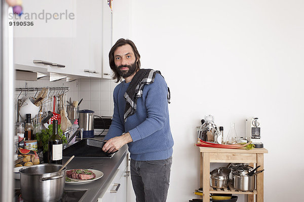 Porträt eines Mannes bei der Zubereitung von Speisen in der heimischen Küche