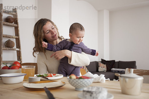 Mutter mit Mädchen am Tisch im Haus