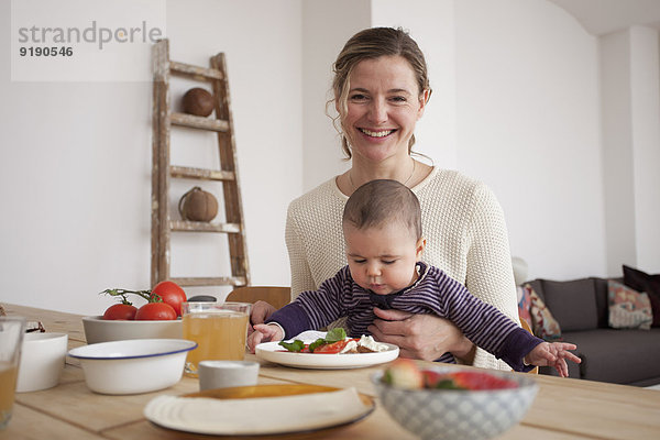 Porträt einer glücklichen Mutter mit einem kleinen Mädchen am Tisch