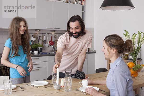 Lächelnde Familie arrangiert Esstisch in der Küche