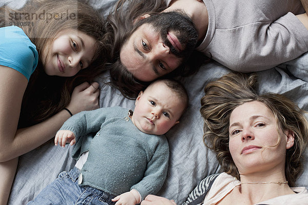 Hochwinkliges Porträt einer Familie  die sich auf dem Bett ausruht