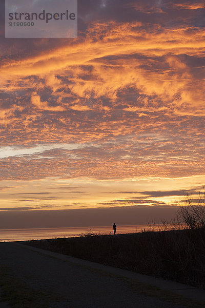 Silhouettenlandschaft vor bewölktem Himmel bei Sonnenuntergang