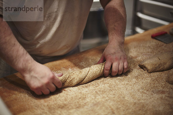 Mittelteil des Mannes bei der Brotzubereitung an der Küchentheke