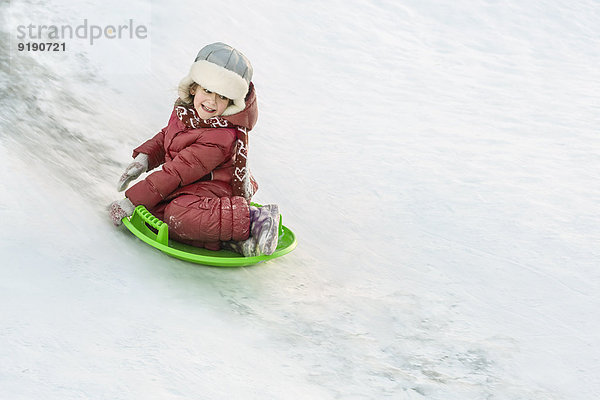 Volle Länge des fröhlichen Mädchenrodelns im Schnee