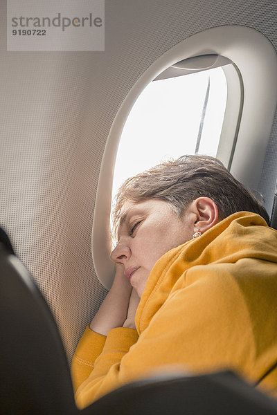 Reife Frau schläft im Flugzeug