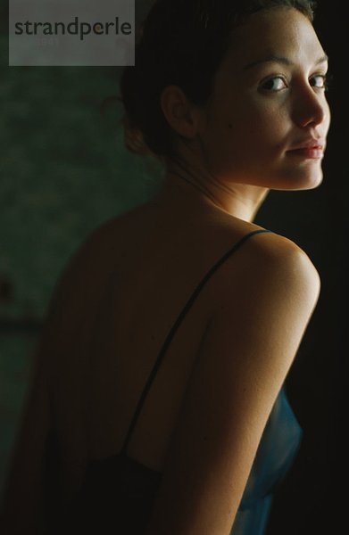 Junge Frau im Nachthemd  Blick über die Schulter zur Kamera