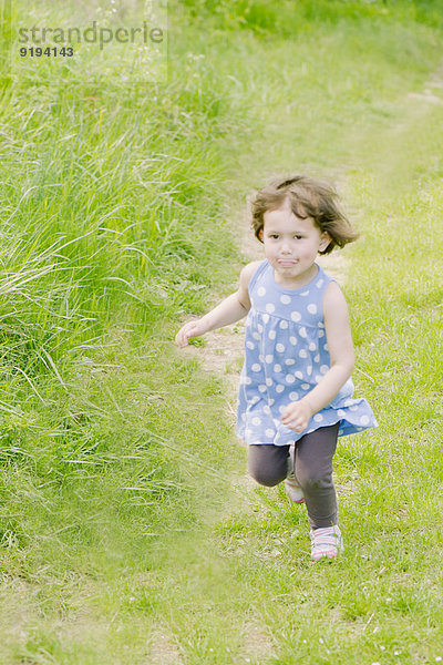 Kleines Mädchen rennt auf dem Weg durch die Landschaft