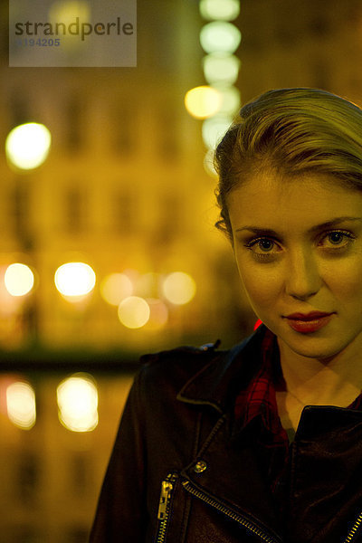 Junge Frau bei Nacht am Fluss  beleuchtet von Stadtlichtern  Portrait