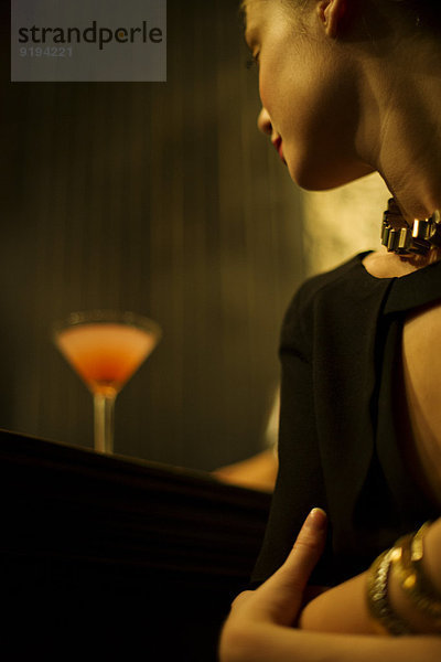 Frau sitzt allein an der Bar mit Cocktail