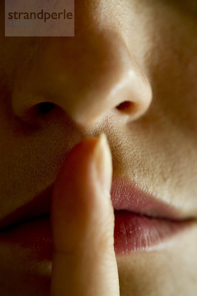 Frau mit Finger auf den Lippen