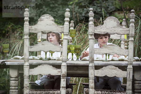 Kinder am Esstisch im Freien sitzend