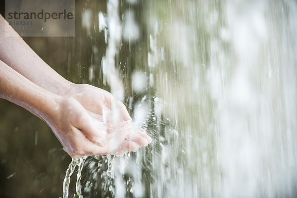 Kind hält Hände unter Wasserfall  abgeschnitten