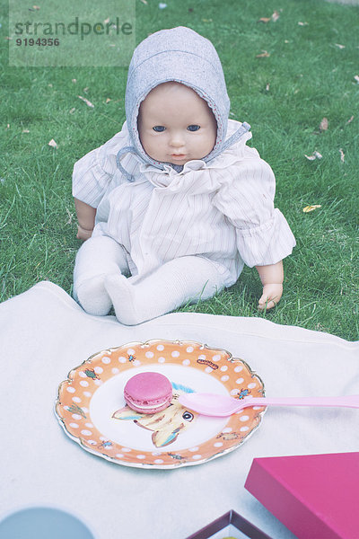 Babypuppe auf Picknickdecke sitzend