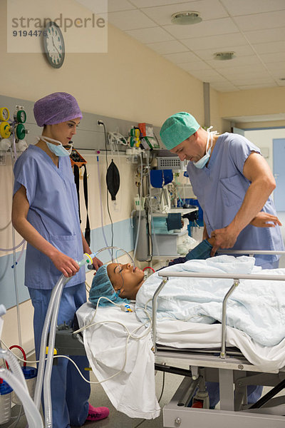 Arzt und Krankenschwester bei einem Patienten im Aufwachraum