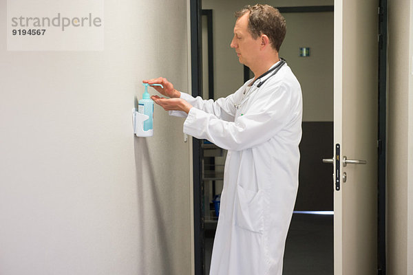 Männlicher Arzt mit hygienischer Handwäsche im Krankenhauszimmer