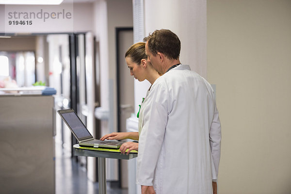 Arzt und Krankenschwester analysieren medizinischen Bericht auf einem Laptop in einem Krankenhaus