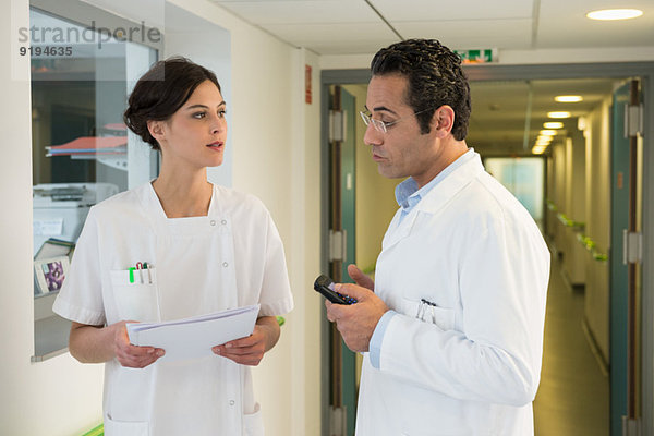 Arzt und Krankenschwester diskutieren im Krankenhausflur