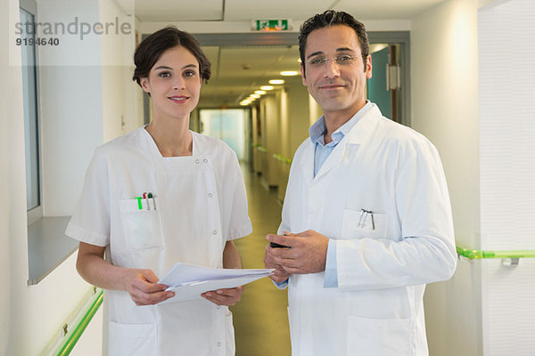 Arzt und Krankenschwester lächeln im Krankenhausflur