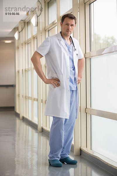 Männlicher Arzt steht in der Nähe eines Fensters in einem Krankenhaus.