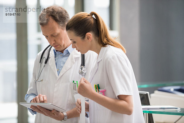 Zwei Ärzte analysieren medizinischen Bericht über digitale Tablette im Krankenhaus