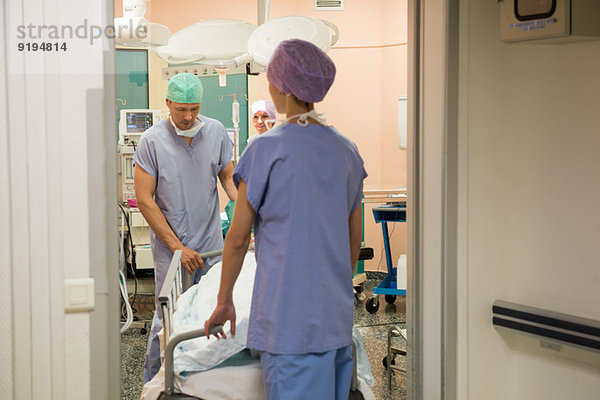 Arzt und Krankenschwester bringen den Patienten in den Operationssaal